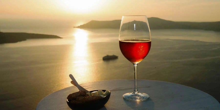 A glass of rich red wine, delectable bites on a plate, complemented by a captivating view. Savoring flavors, embracing beauty.